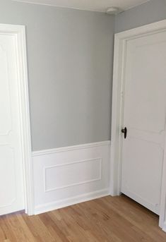 an empty room with two white doors and hard wood flooring on the other side