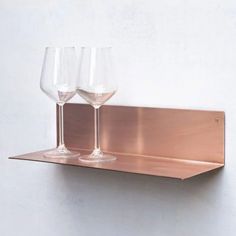 two wine glasses sitting on top of a metal shelf