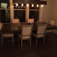 a dining room table with white chairs and lights