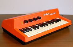 an orange keyboard sitting on top of a wooden table