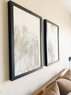 two framed pictures hang on the wall above a couch