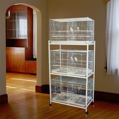 two birds sit on top of three cages in the middle of an empty living room