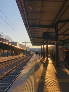 people are waiting at the train station for their trains to arrive and go out on the tracks