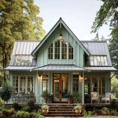 a green house with lots of windows and potted plants on the front porch area