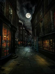 an empty street at night with the full moon in the sky and buildings on either side