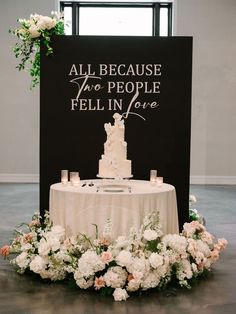 a wedding cake sitting on top of a table next to a sign that says, all because two people fell in love