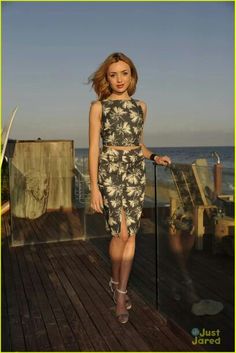 a woman standing on top of a wooden deck next to the ocean and holding a cane