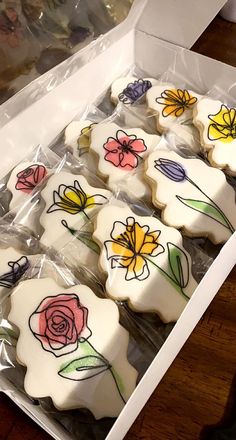 a box filled with decorated cookies on top of a wooden table