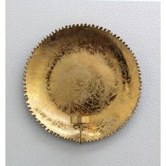 a gold plate on a white wall with a metal handle in the shape of a star