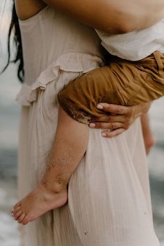 a close up of a woman holding a child on her back with sand all over her arm