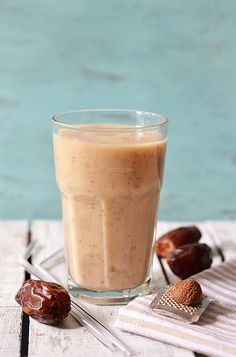 a glass filled with liquid sitting on top of a wooden table next to an acorn