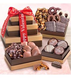 three tiered boxes filled with assorted chocolates and pretzels, along with a red ribbon that says happy valentine's day