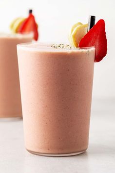 two smoothies with strawberries and lemon wedges on the top are ready to be eaten