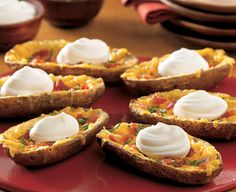 a red plate topped with mini quiches covered in sour cream and toppings on top