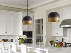 a large kitchen with white cabinets and marble counter tops, two pendant lights hanging over the island