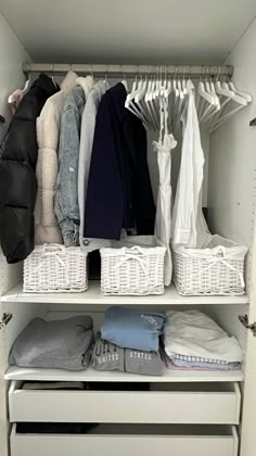 an organized closet with white baskets and clothes