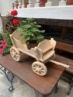 a wooden toy horse drawn carriage with potted plants on the back seat and bench