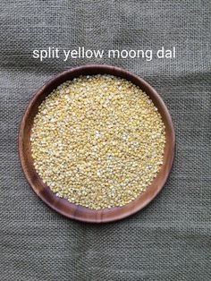 a wooden bowl filled with yellow and white grains on top of a gray cloth covered tablecloth