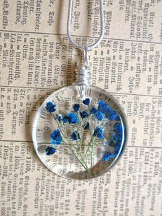 a blue flower in a glass pendant on a chain