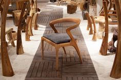 a wooden chair sitting in the middle of a room filled with chairs and stools