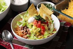 a salad with tortilla chips, tomatoes and lettuce on the side