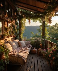 a porch covered in lots of flowers and greenery next to a wooden deck with a couch on it