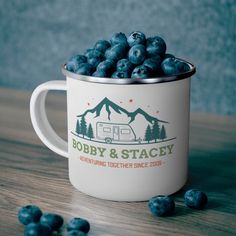 a camper mug filled with blueberries on top of a wooden table