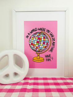 a pink and white checkered table cloth with a peace sign on it next to a framed print that says, i am a world where you can always have fun