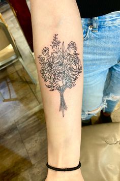 a woman with a tattoo on her arm has a bouquet of flowers tattooed on her leg