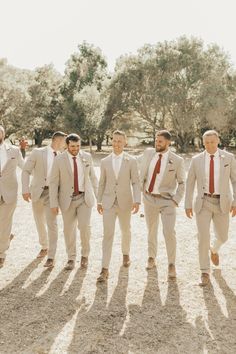 a group of men standing next to each other wearing white suits and red neck ties