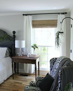 a bed room with a neatly made bed next to a chair and a table in front of a window