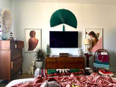 a bedroom with a large flat screen tv mounted to the wall above a dresser and bed