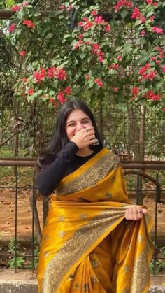 a woman in a yellow sari sitting on a bench with her hand over her mouth