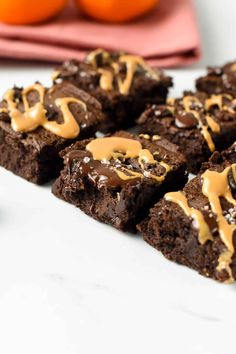 chocolate brownies with caramel drizzle on top and oranges in the background