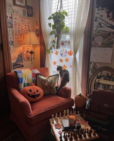 a cat sitting on top of a couch next to a table filled with chess pieces