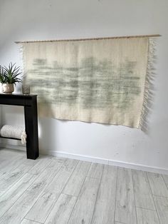 a white wall with a rug hanging from it's side next to a black table