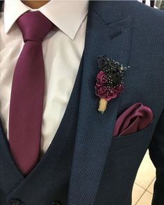 a man wearing a suit and tie with a boutonniere on his lapel