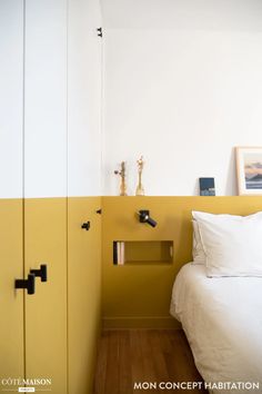 a bed sitting next to a yellow and white wall