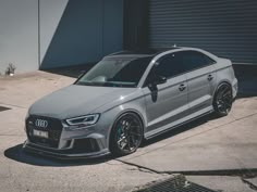 a silver car parked in front of a garage