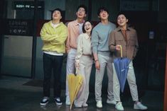 four people standing in front of a building holding umbrellas