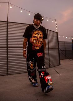 a man holding a skateboard in his right hand while standing next to a fence