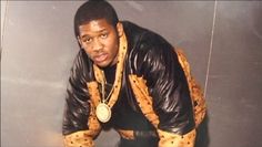 a man in black leather jacket and gold chain around his neck posing for the camera