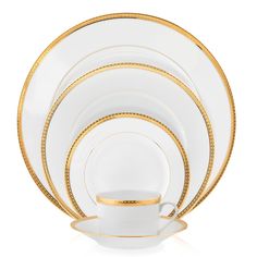 white and gold dinnerware with golden trimmings on the rim, set against a white background