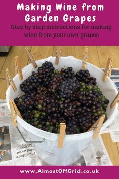 a bucket filled with grapes sitting on top of a wooden table next to newspaper paper