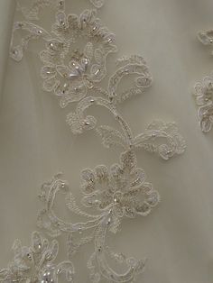 an embroidered white fabric with flowers and pearls on the bottom, along with beading