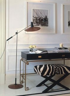 a black and white zebra print ottoman sits in front of a desk with a lamp on it