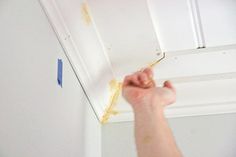 a person is painting the ceiling with white paint and brown stains on it's walls