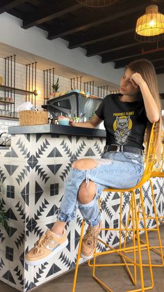 a woman sitting in a yellow chair next to a counter