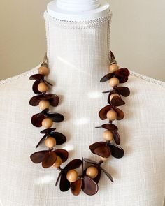 A striking necklace inspired by nature! The tagua petals and bombona seeds are arranged in such a way that they look like real orchids with their small buttons. Pair this wonderful necklace with a solid top or a simple cocktail dress. Thanks to the natural characteristics you can be sure yours is unique. Tagua, also called the vegetable ivory is the seed of a palm tree that grows in the tropical rainforests of several South American countries including Colombia and Ecuador. Handmade in the USA. Artisan Necklace With Natural Variations And Adjustable Fit, Adjustable Wooden Beads Necklace In Nature-inspired Style, Handmade Brown Shell Necklace For Gift, Unique Adjustable Necklace With Natural Variations, Adjustable Nature-inspired Necklaces With Natural Variations, Unique Brown Fair Trade Necklace, Unique Brown Long Necklace, Unique Long Brown Necklace, Adjustable Long Nature-inspired Necklace