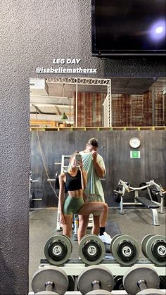 a man and woman standing next to each other in front of a mirror with dumbbells